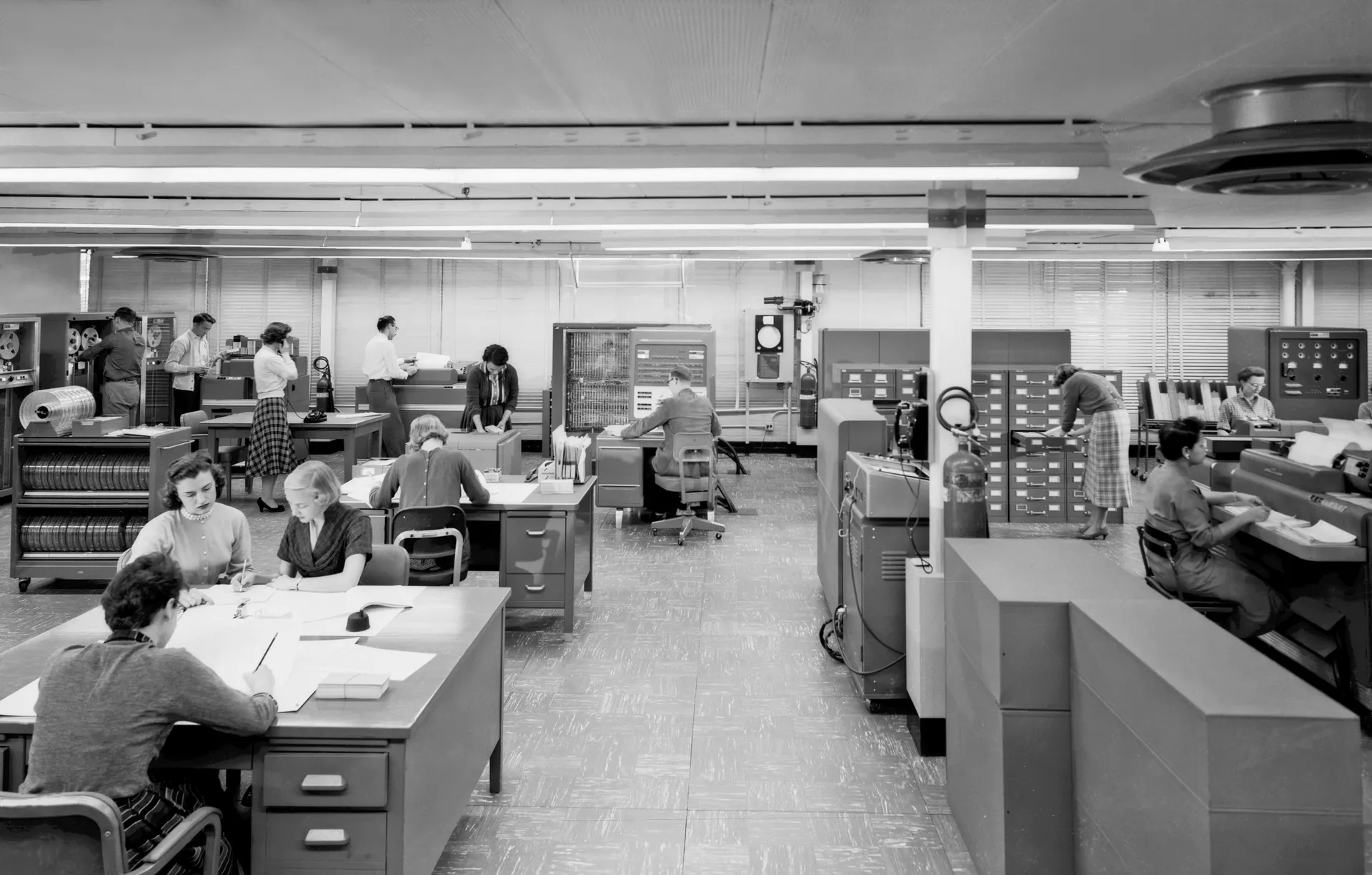 Rows of desks, card machines and staff in Langley’s IBM 704 computing room.