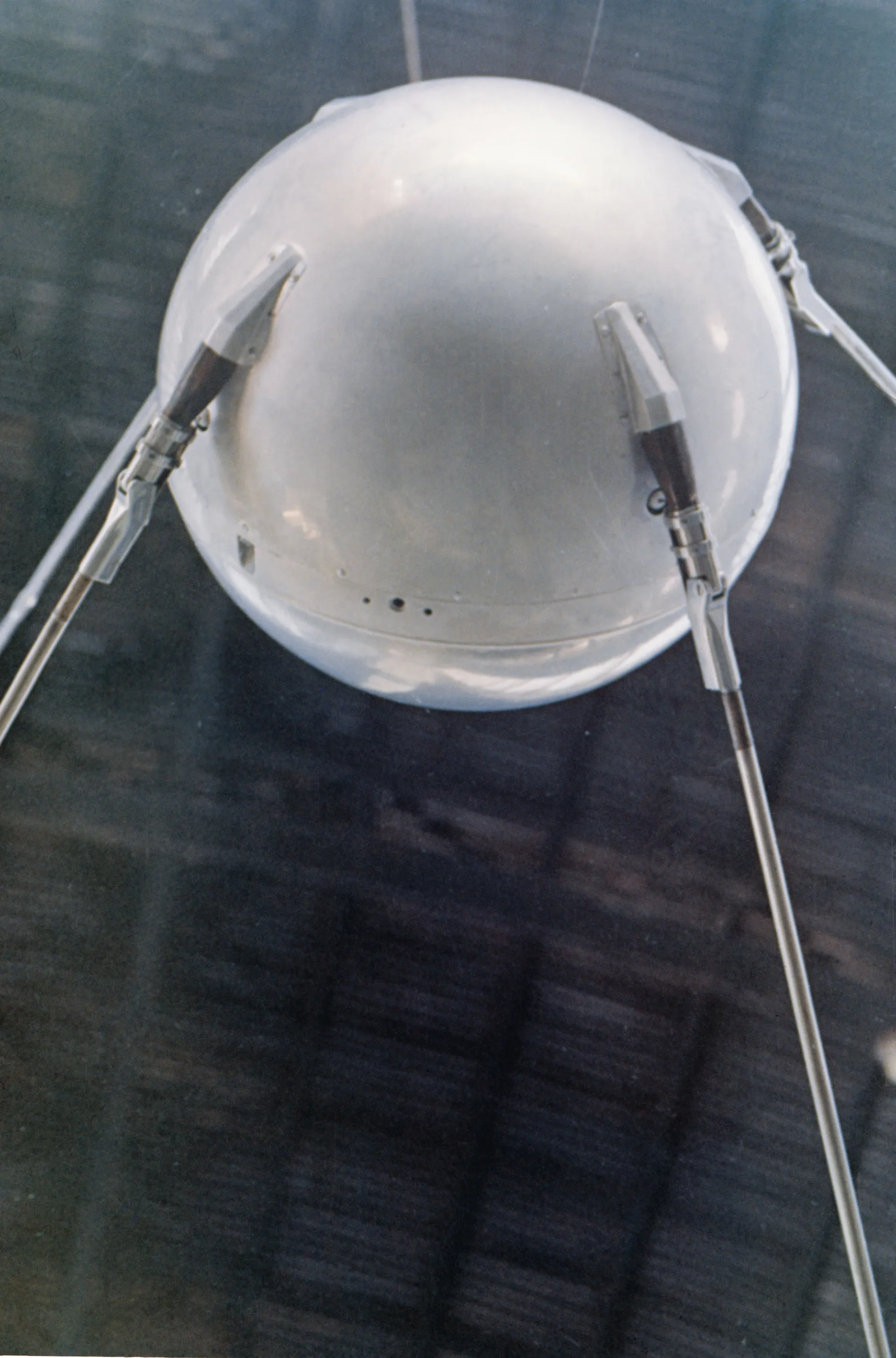A full-scale model of Sputnik 1: a polished metal sphere with four long antennas swept back.