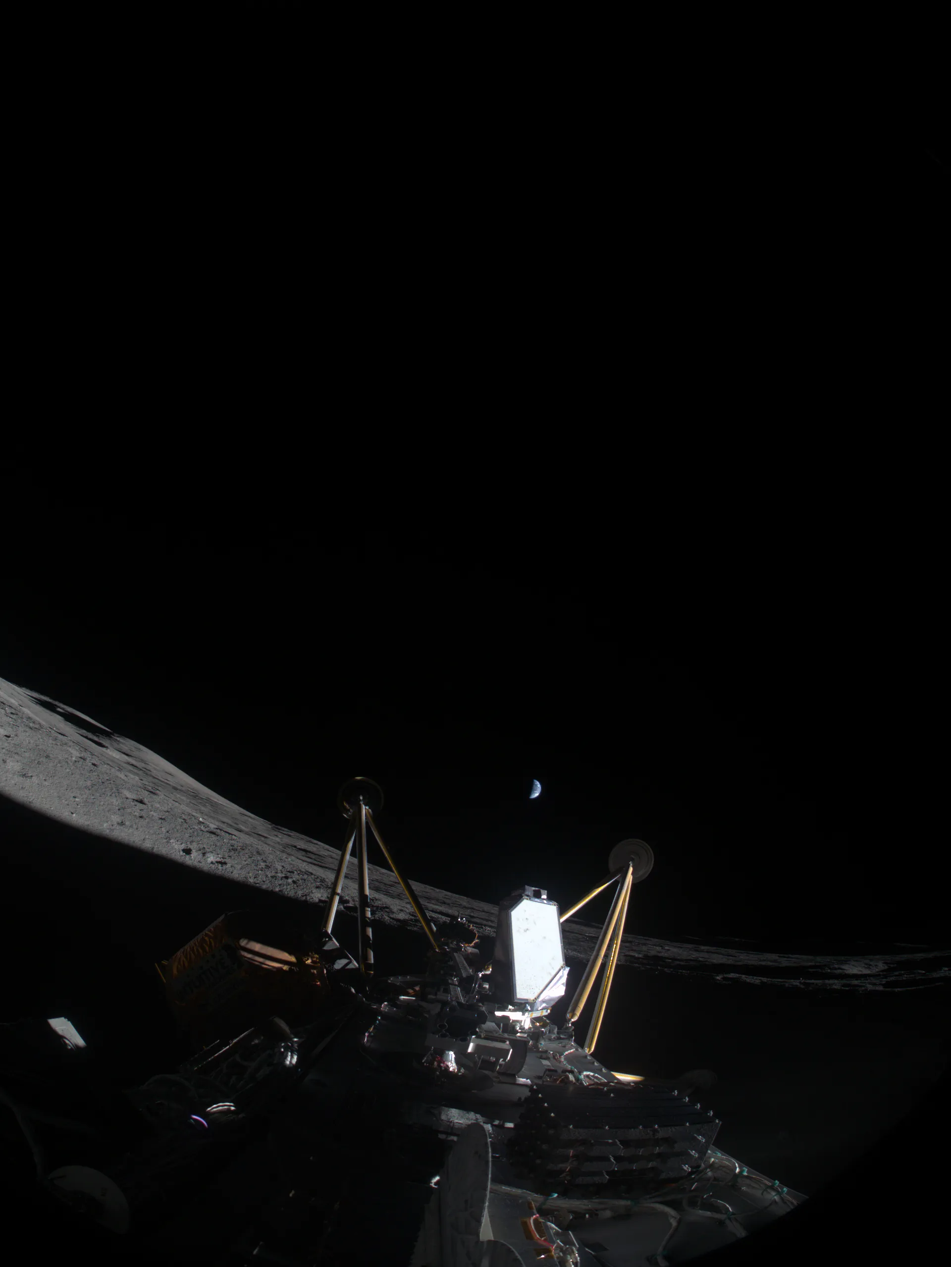 A view from a lander lying on its side: a gold antenna mast and equipment in the foreground, the curved lunar horizon beyond, and a thin crescent Earth in the black sky.