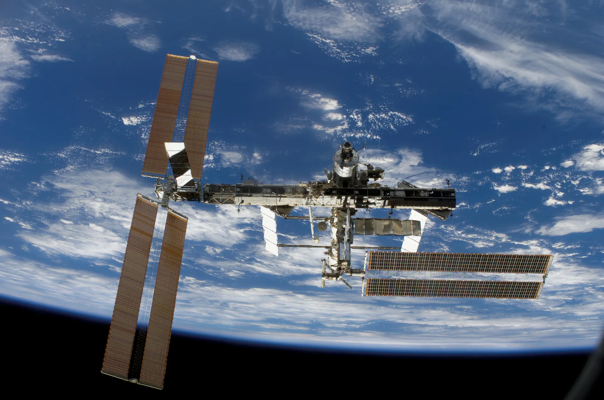 The station over Earth with a partial truss and solar arrays at different angles.
