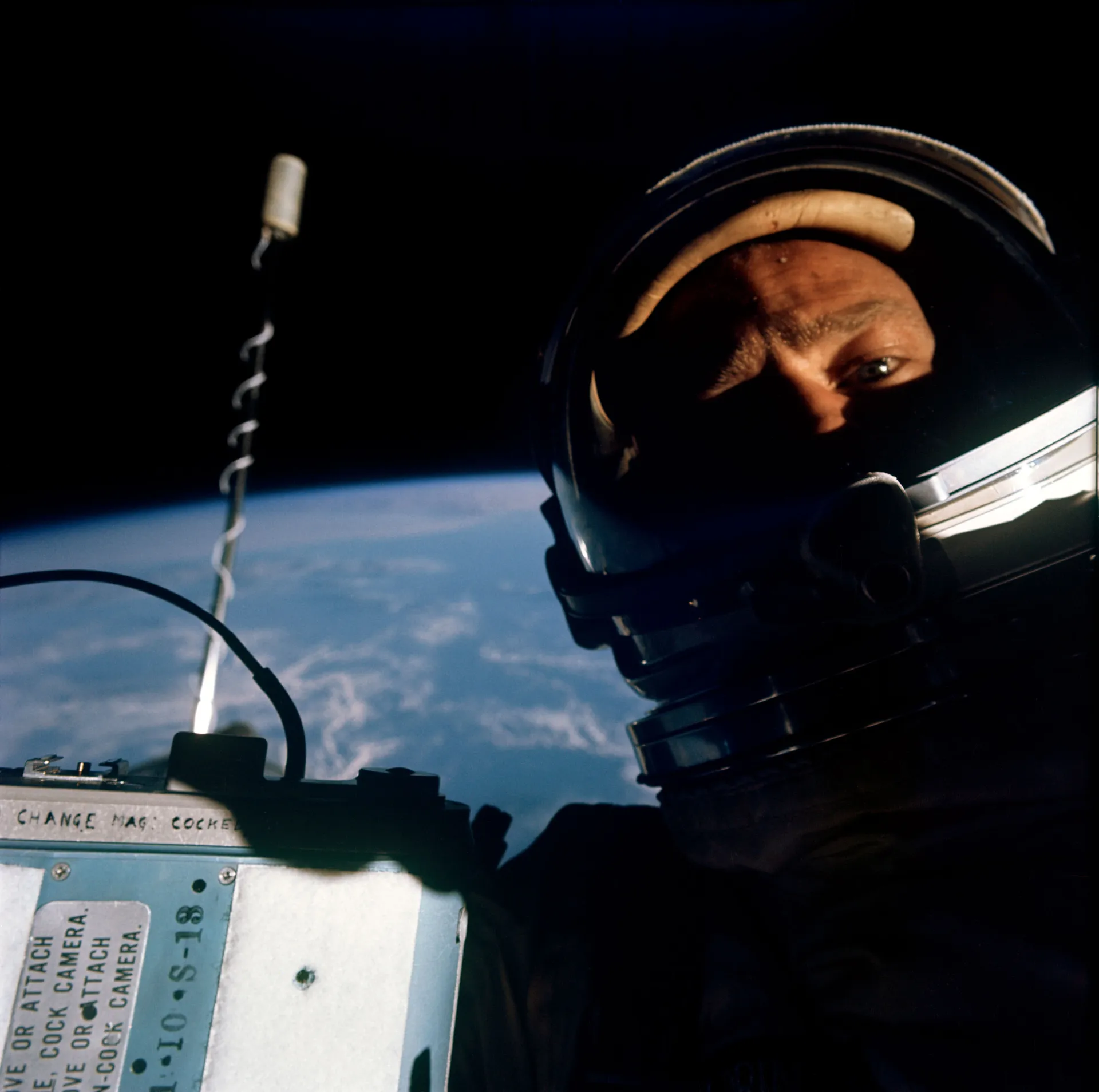 Buzz Aldrin photographs himself in his helmet outside Gemini 12, with Earth’s edge behind.