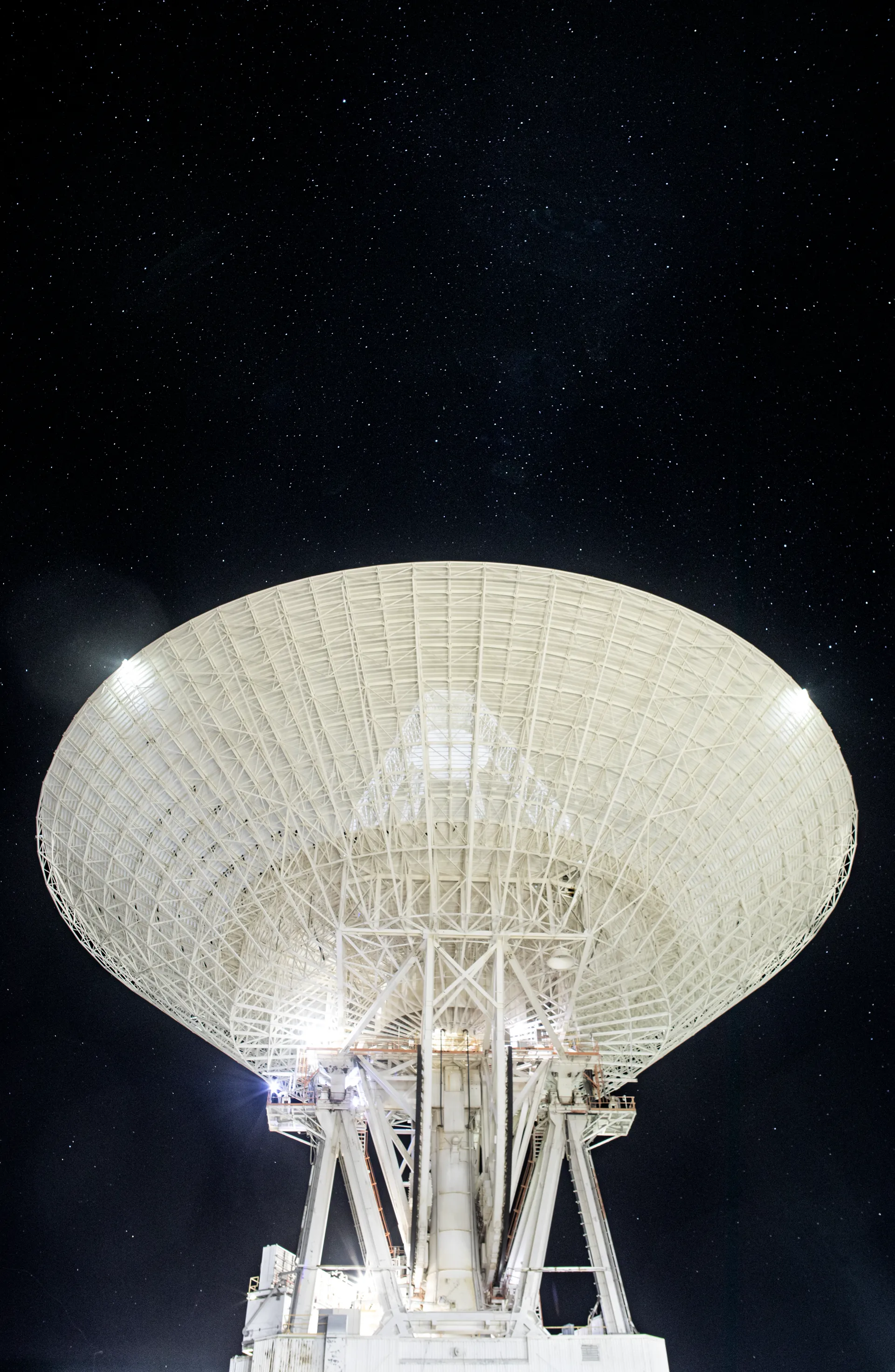 The 70-meter Goldstone antenna pointing up into a star-filled night sky.