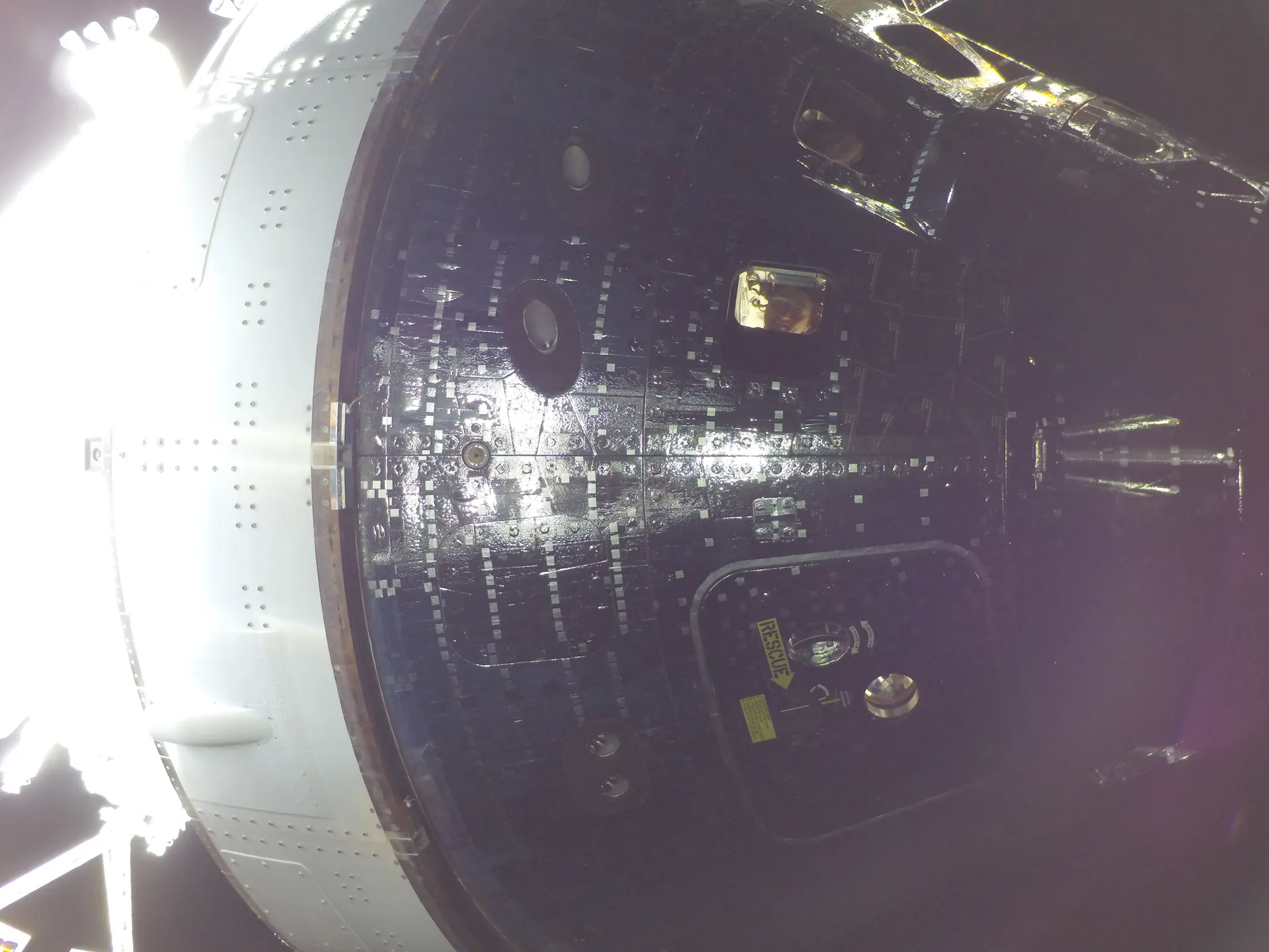 Christina Koch and Reid Wiseman seen through two of Orion’s windows, photographed from outside the spacecraft.
