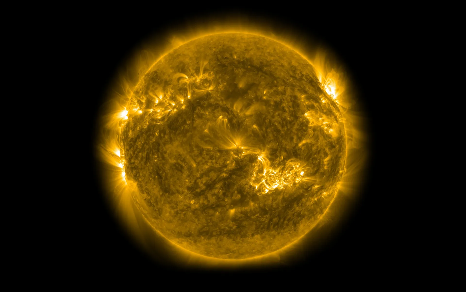 The same view of the Sun crowded with bright looping active regions and wisps of corona.