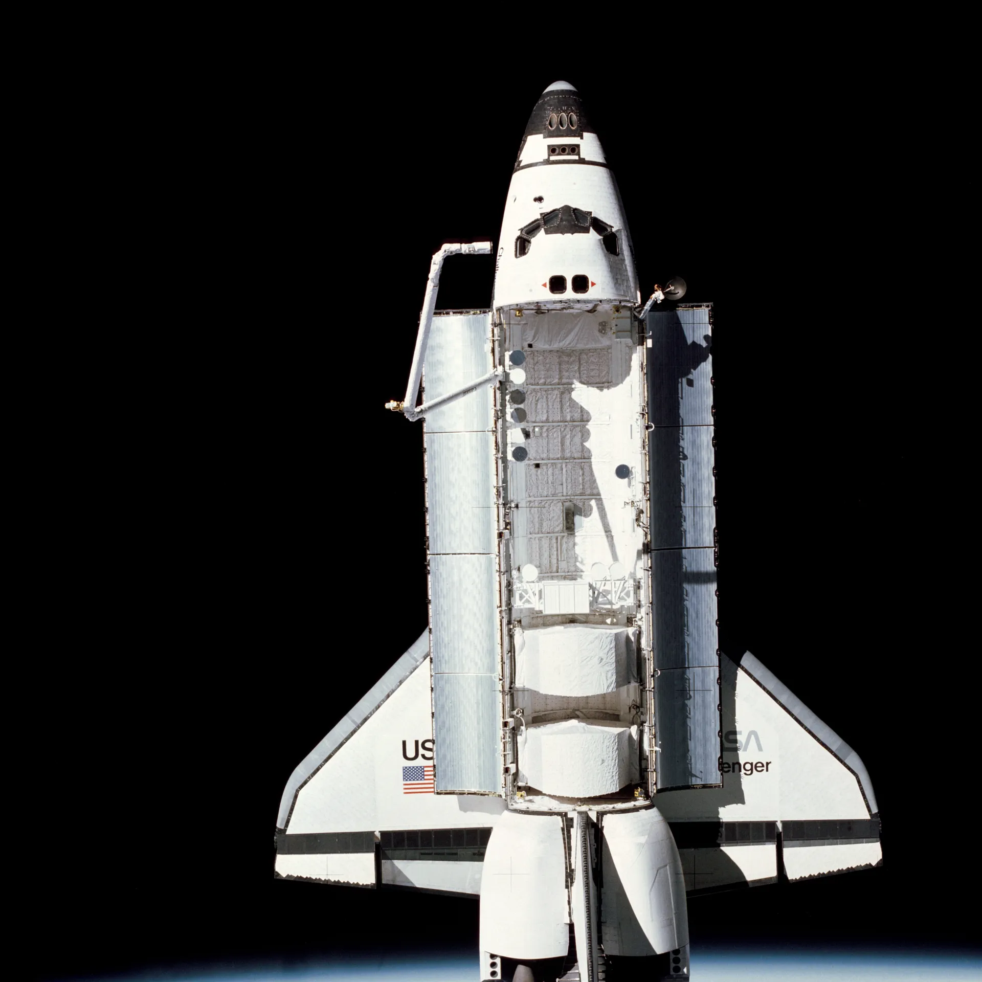 Challenger in orbit against black space with its payload bay doors open and the robotic arm raised, Earth’s edge below.